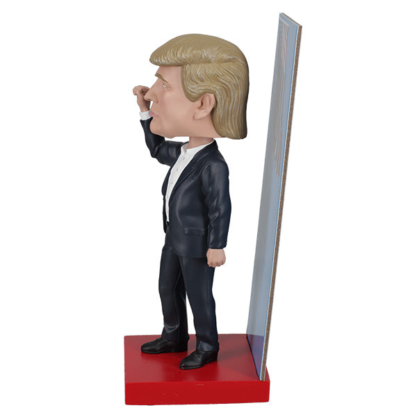 2025 Inauguration Limited Edition Donald Trump Bobblehead featuring a raised fist and American flag backdrop displayed on a shelf.
