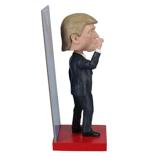 2025 Inauguration Limited Edition Donald Trump Bobblehead featuring a raised fist and American flag backdrop displayed on a shelf.