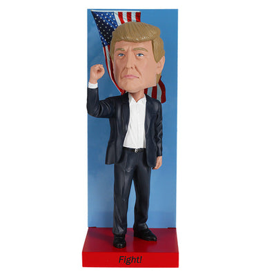 2025 Inauguration Limited Edition Donald Trump Bobblehead featuring a raised fist and American flag backdrop displayed on a shelf.