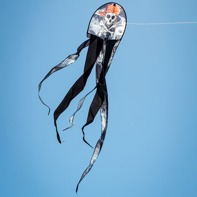 22 inch Smokin' Pirate Dancing Dragon Kite flying in the air with vibrant pirate and dragon designs, showcasing long flowing tails in a clear sky.