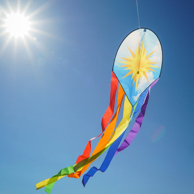 22-inch Sun & Rainbow Dancing Dragon Kite with colorful tails flying against a clear blue sky during a sunny day.