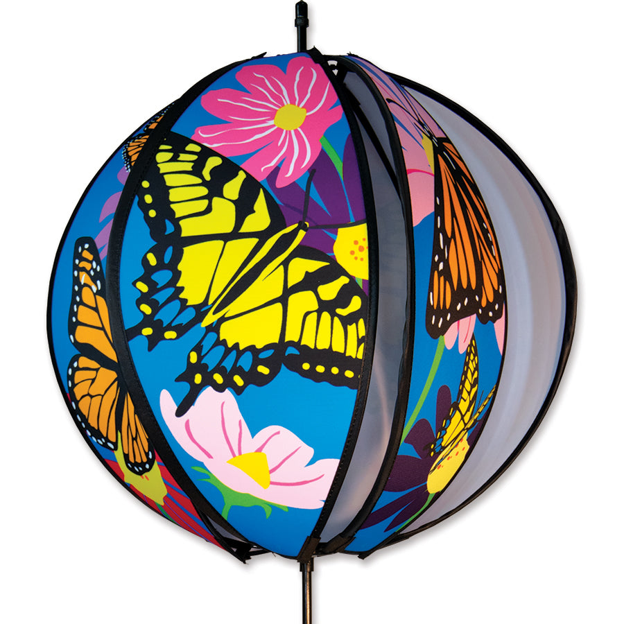 Colorful 24 in. Ball Spinner featuring butterflies and flowers, spinning gracefully in a garden setting, accented by lush greenery.