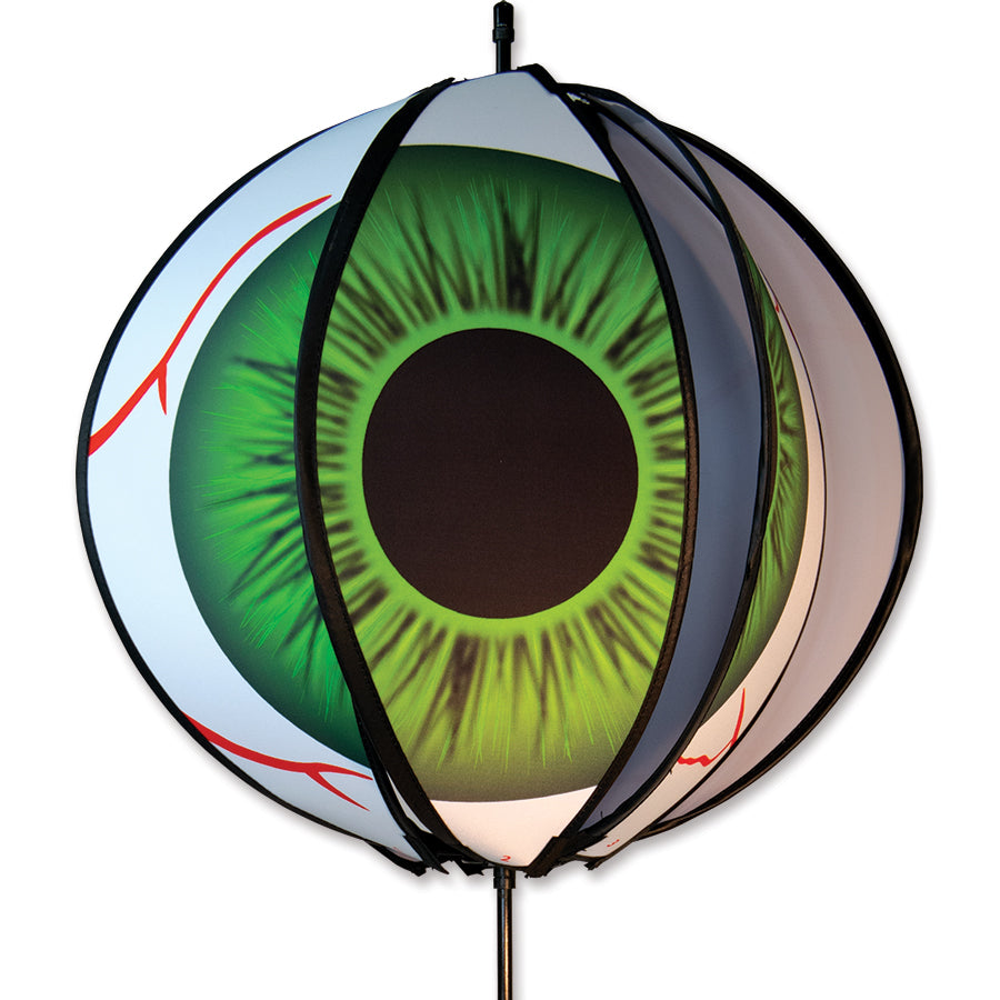 24 in. Ball Spinner - Eyeball featuring a vivid bloodshot eyeball design in a colorful spinning display placed in an outdoor garden setting.