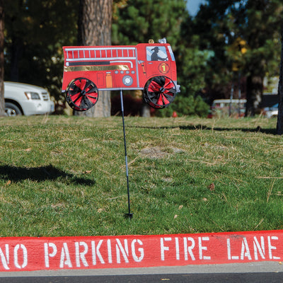 Vibrant 24'' Fire Truck Spinner in a garden setting with spinning wheels, showcasing a charming red fire truck design in motion.