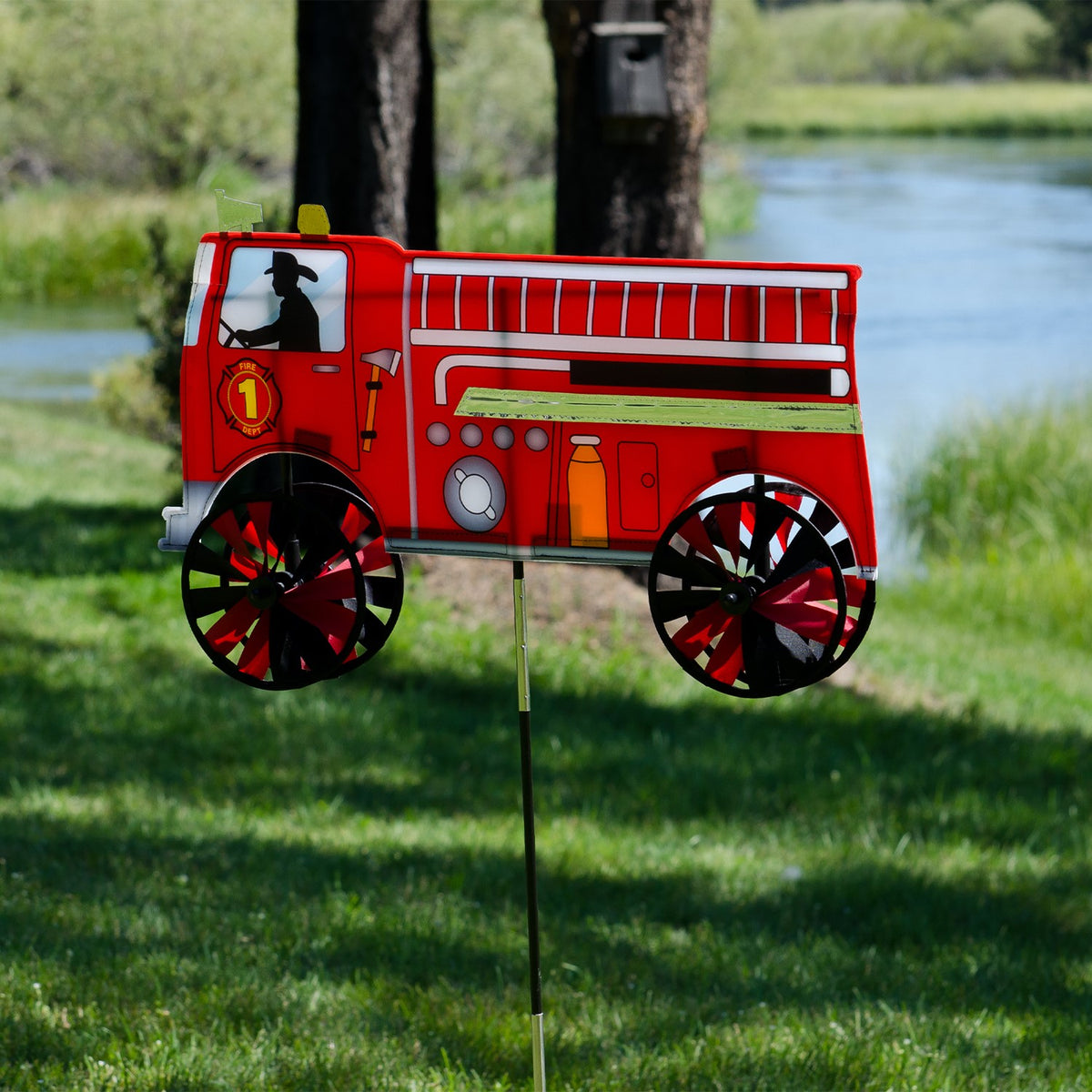 Vibrant 24'' Fire Truck Spinner in a garden setting with spinning wheels, showcasing a charming red fire truck design in motion.