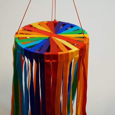 24-inch Rainbow Ribbon Windsock featuring shiny satin ribbons in a spectrum of colors, hanging outdoors, gently swaying in the breeze.
