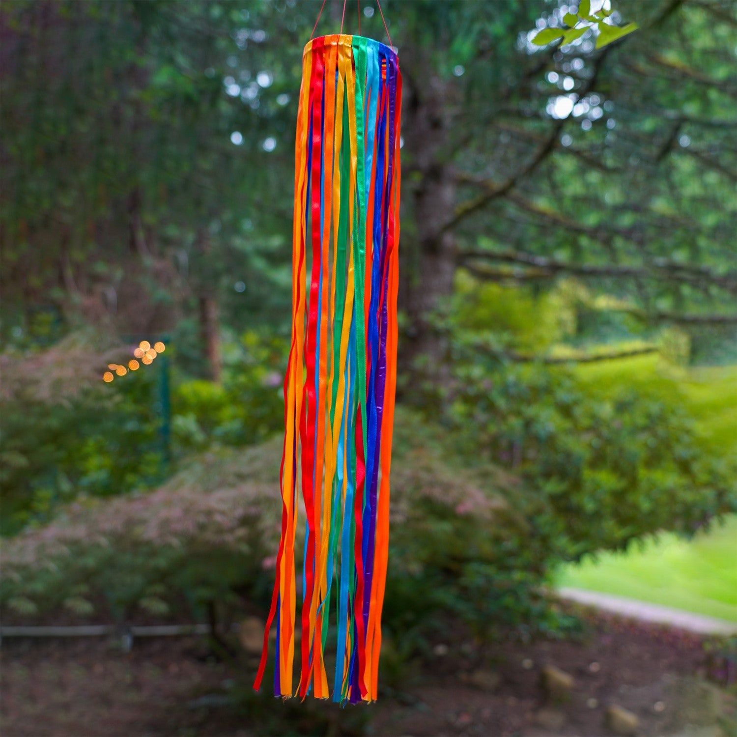 24-inch Rainbow Ribbon Windsock featuring shiny satin ribbons in a spectrum of colors, hanging outdoors, gently swaying in the breeze.