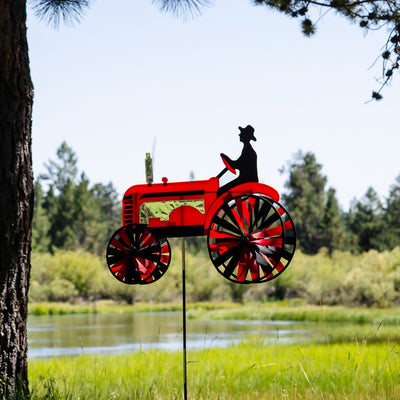 24-inch Red Tractor Spinner with four vibrant spinning wheels and applique details, delightfully showcased in an outdoor garden setting.