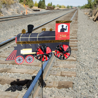 24-inch Steam Engine Spinner with vibrant colors and shiny applique accents, spinning gently in a garden setting, evoking retro train nostalgia.