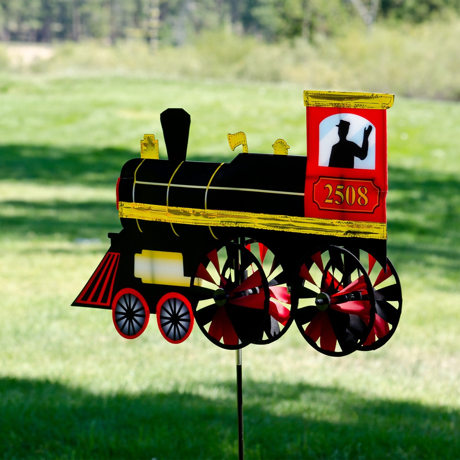 24-inch Steam Engine Spinner with vibrant colors and shiny applique accents, spinning gently in a garden setting, evoking retro train nostalgia.