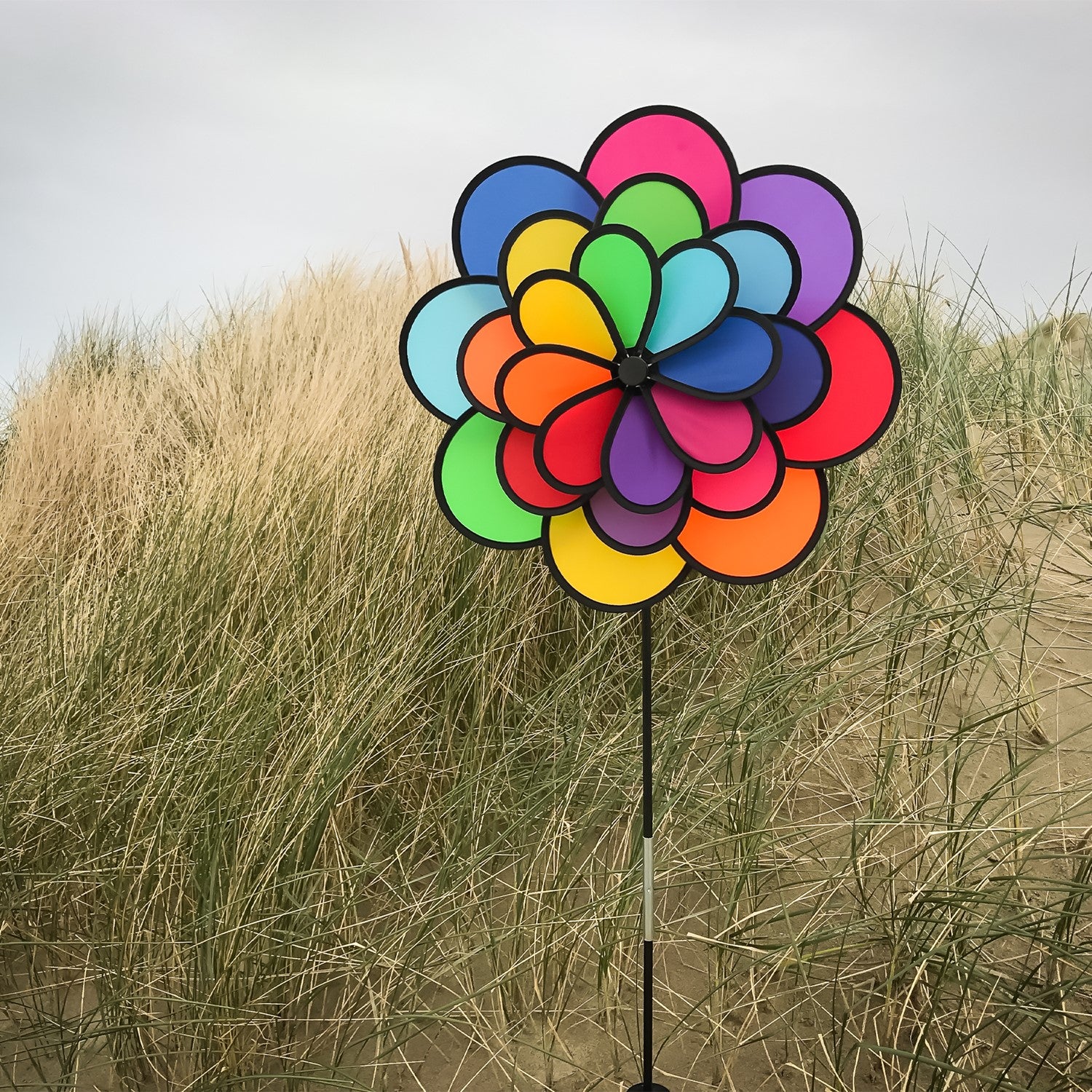 24-Petal Flower Triple Wheel Spinner featuring vibrant rainbow-colored petals spinning in a garden setting, creating a playful decoration.