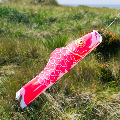 Colorful 24" Pink Koi windsock hanging outdoors, showcasing its vibrant design and fluttering in the breeze.