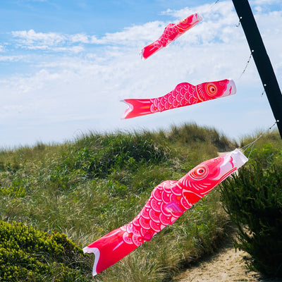 Colorful 24" Pink Koi windsock hanging outdoors, showcasing its vibrant design and fluttering in the breeze.