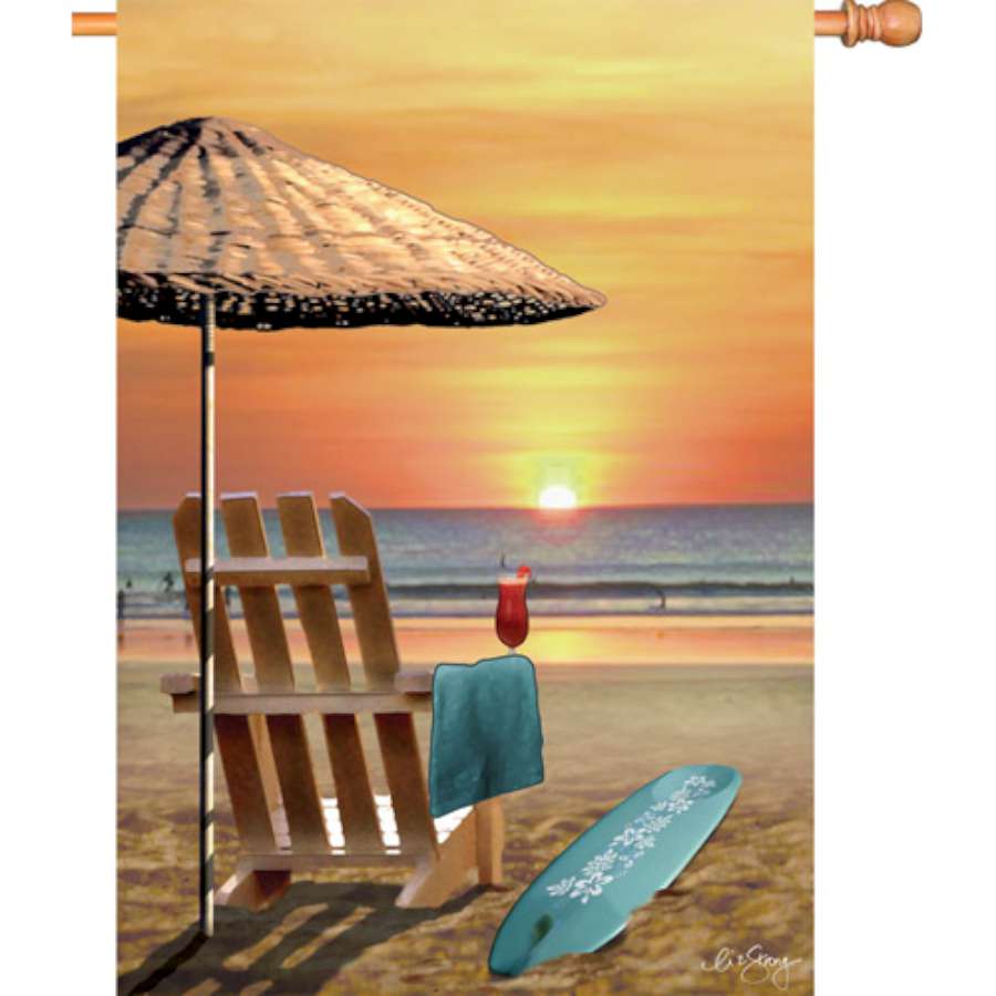 28 in. Bali Sunset house flag showcasing a vibrant, double-sided sunset design, displayed on an outdoor flagpole in a garden setting.