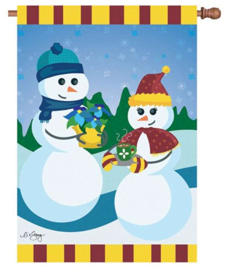 28 in. Dating on a Snowy Slope winter flag displaying a picturesque snowy landscape on an outdoor flag stand, surrounded by festive decorations.