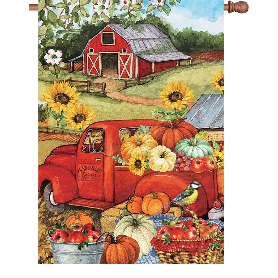28 in. house flag featuring an illuminated autumn truck design with pumpkins and falling leaves displayed in a garden setting.