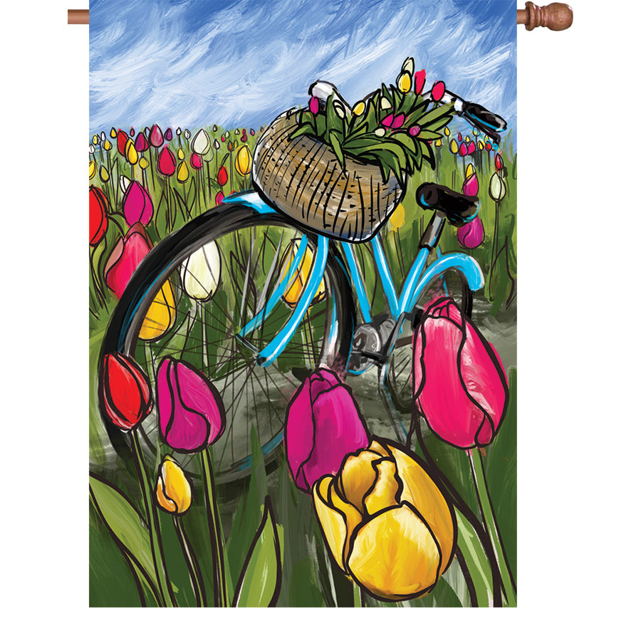 28 in. Flag - Bike Through the Tulips displayed outdoors, showcasing a decorative design of a bicycle surrounded by colorful tulips.