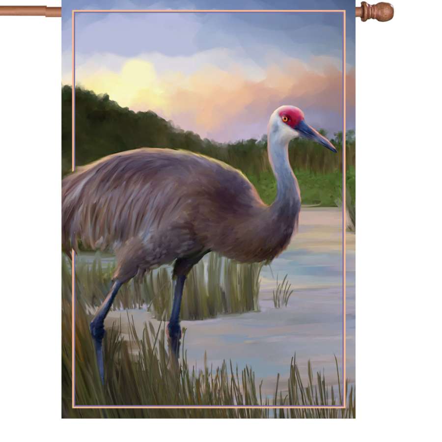 Illuminated 28 in. Sandhill Crane flag made from durable polyester, displaying vibrant colors in an outdoor garden setting.