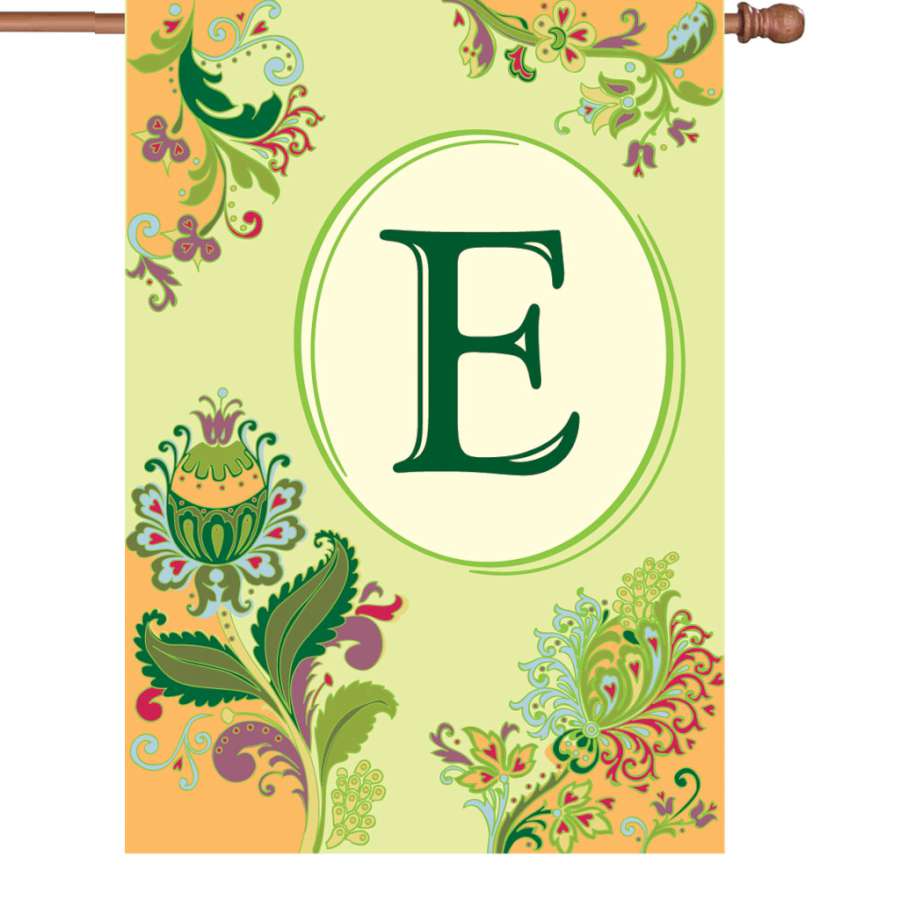 28 in. Spring Monogram Flag - E displayed in a garden setting with floral designs surrounding the letter E, showcasing vibrant colors and seasonal charm.