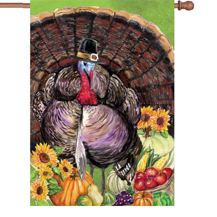 28 in. Turkey Pilgrim flag featuring a festive turkey design illuminated, displayed outdoors in a garden setting during autumn.