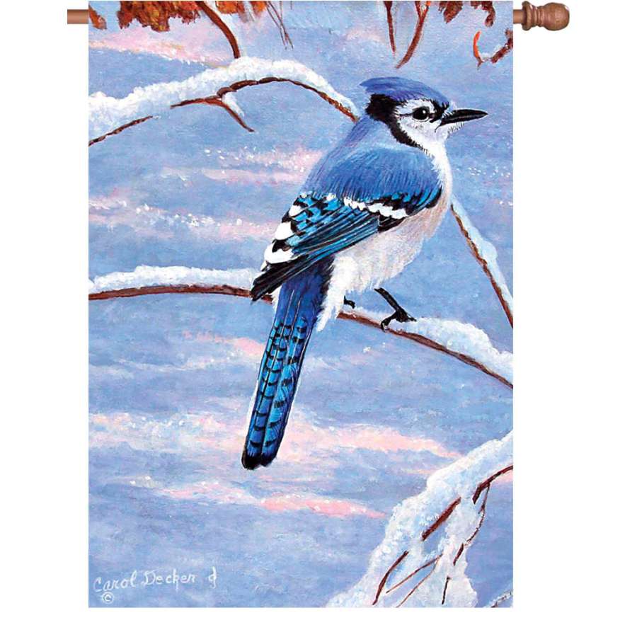 28 in. Winter Blue Jay flag displaying a vibrant blue jay design, hanging on a flag pole in a snowy outdoor setting.
