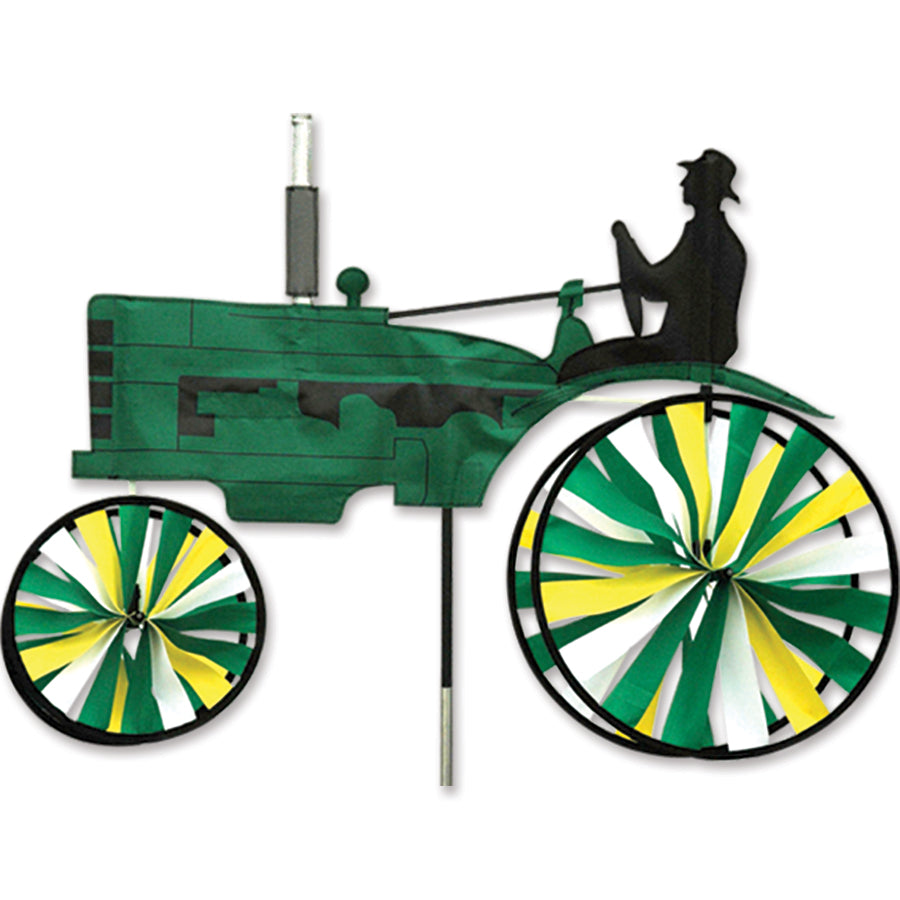 29 in. Old Tractor Spinner in green, featuring a vintage tractor design, displayed in a garden setting during a sunny day.