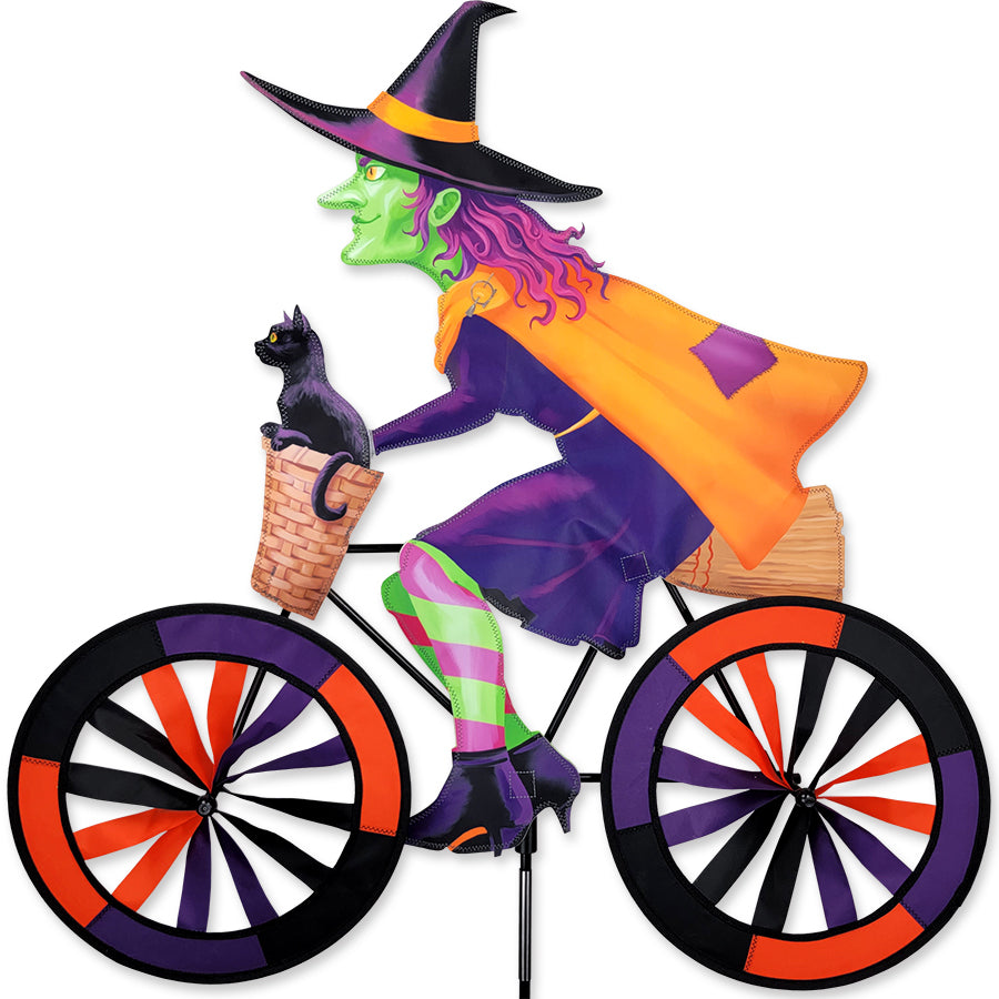 30 in. Bike Spinner featuring a colorful witch design on a bicycle, spinning gracefully in an outdoor garden setting.