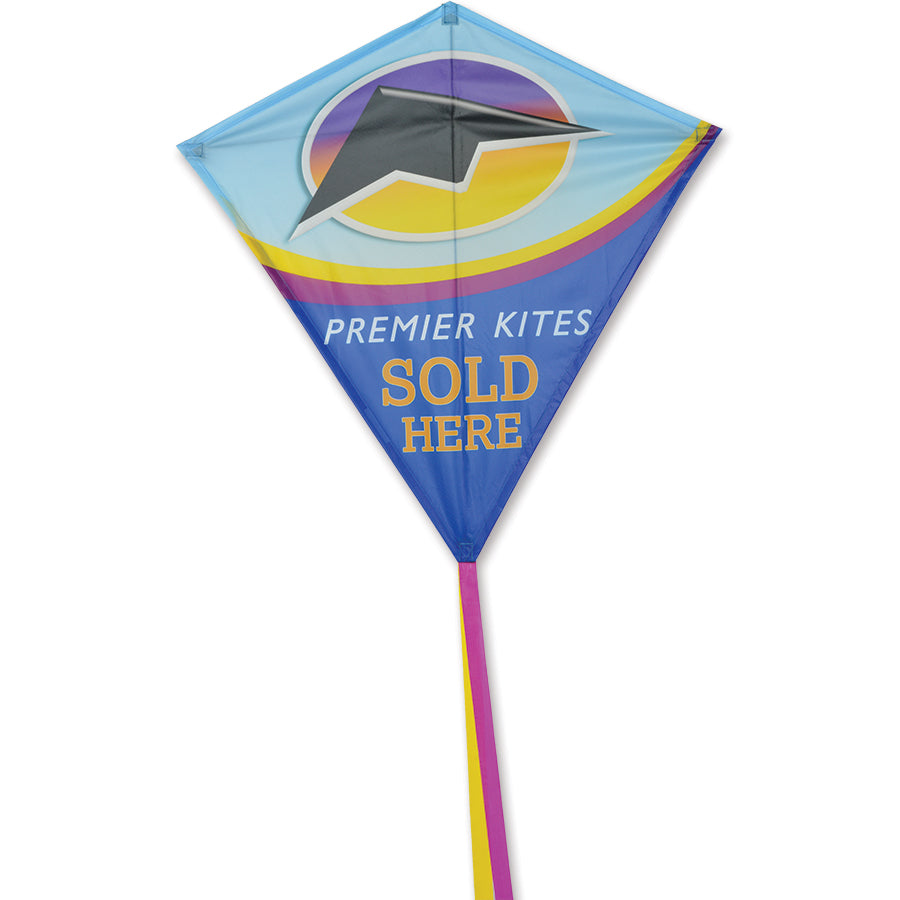 30 in. Diamond Kite with colorful graphics soaring in a clear blue sky, showcasing its ripstop polyester fabric and vibrant design.