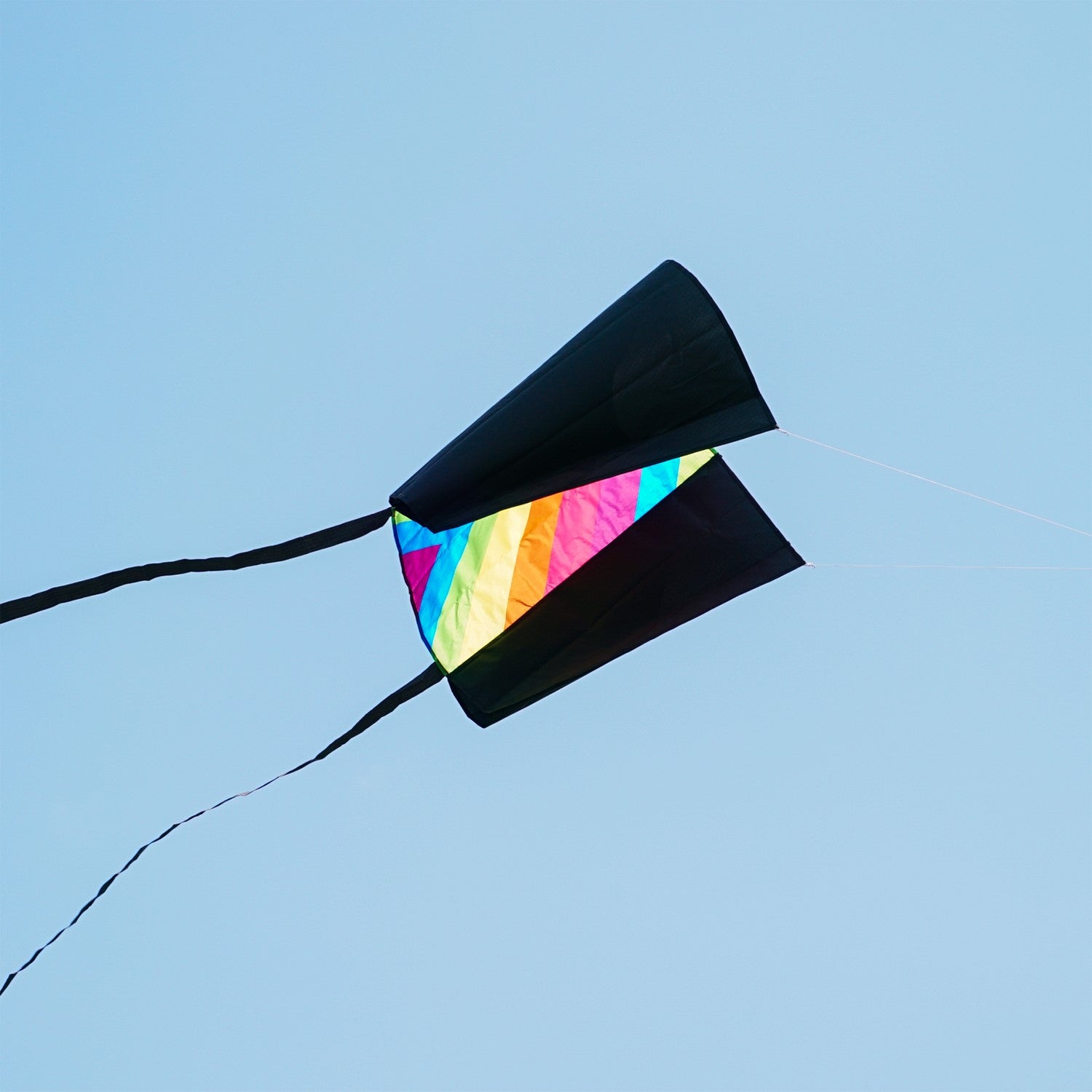30-inch Neon Fiesta Stripe Sled Kite in vibrant colors flying high with black tails, suitable for beginners and easy to pack.