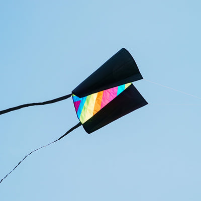 30-inch Neon Fiesta Stripe Sled Kite in vibrant colors flying high with black tails, suitable for beginners and easy to pack.