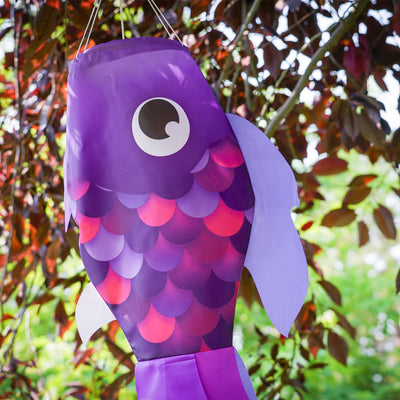 30" Lavender Damsel Fish wind sock with vibrant lavender coloration and free-flowing fins displayed outdoors in a garden setting.