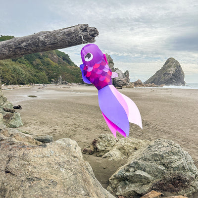 30" Lavender Damsel Fish wind sock with vibrant lavender coloration and free-flowing fins displayed outdoors in a garden setting.