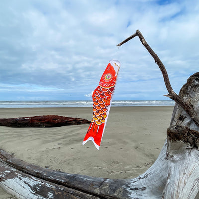 36-inch vibrant Orange Koi windsock, crafted from weather-resistant fabric, elegantly displayed in a garden setting to add color and charm.