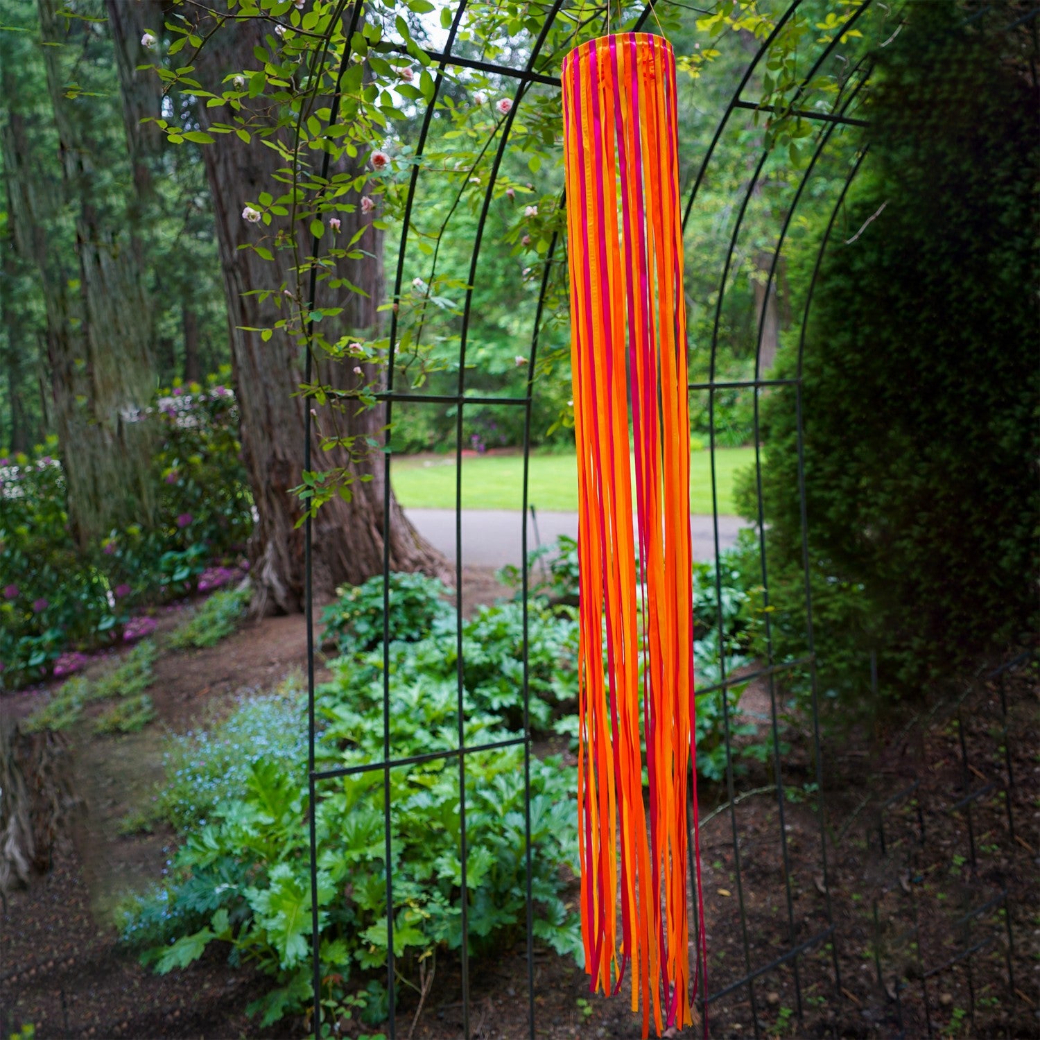 39-inch Sunset Ribbon Windsock featuring vibrant satin ribbons in fuchsia, orange, and yellow displayed outdoors, swaying gently in the wind.