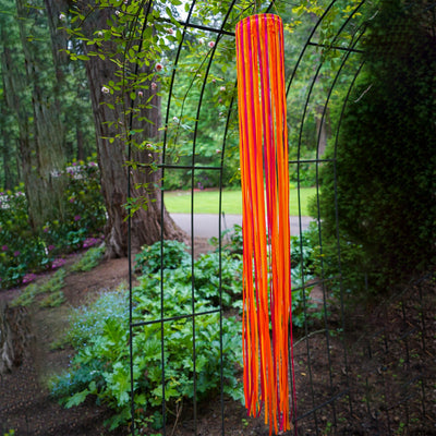39-inch Sunset Ribbon Windsock featuring vibrant satin ribbons in fuchsia, orange, and yellow displayed outdoors, swaying gently in the wind.
