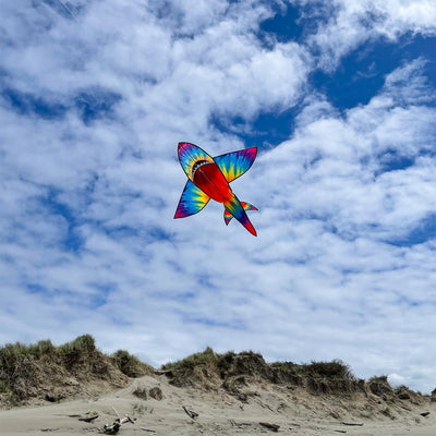 5-foot 3D Tie Dye Shark Kite flying high against a blue sky, showcasing its vibrant colors and fun design as it swims through the air.
