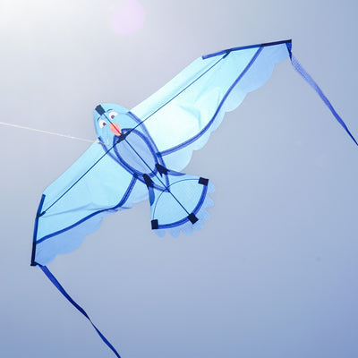 40-inch Blue Bitty Bird Kite featuring a colorful design with attached streamer tails soaring in a clear blue sky.