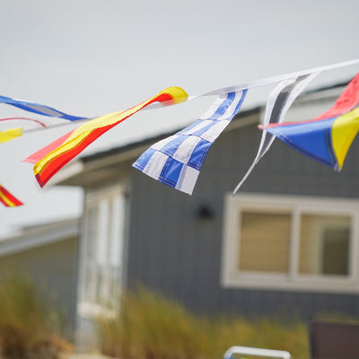 40 Piece Maritime Signal Flags on String decorated across a wooden terrace, featuring various colors and nautical designs that represent maritime communication.