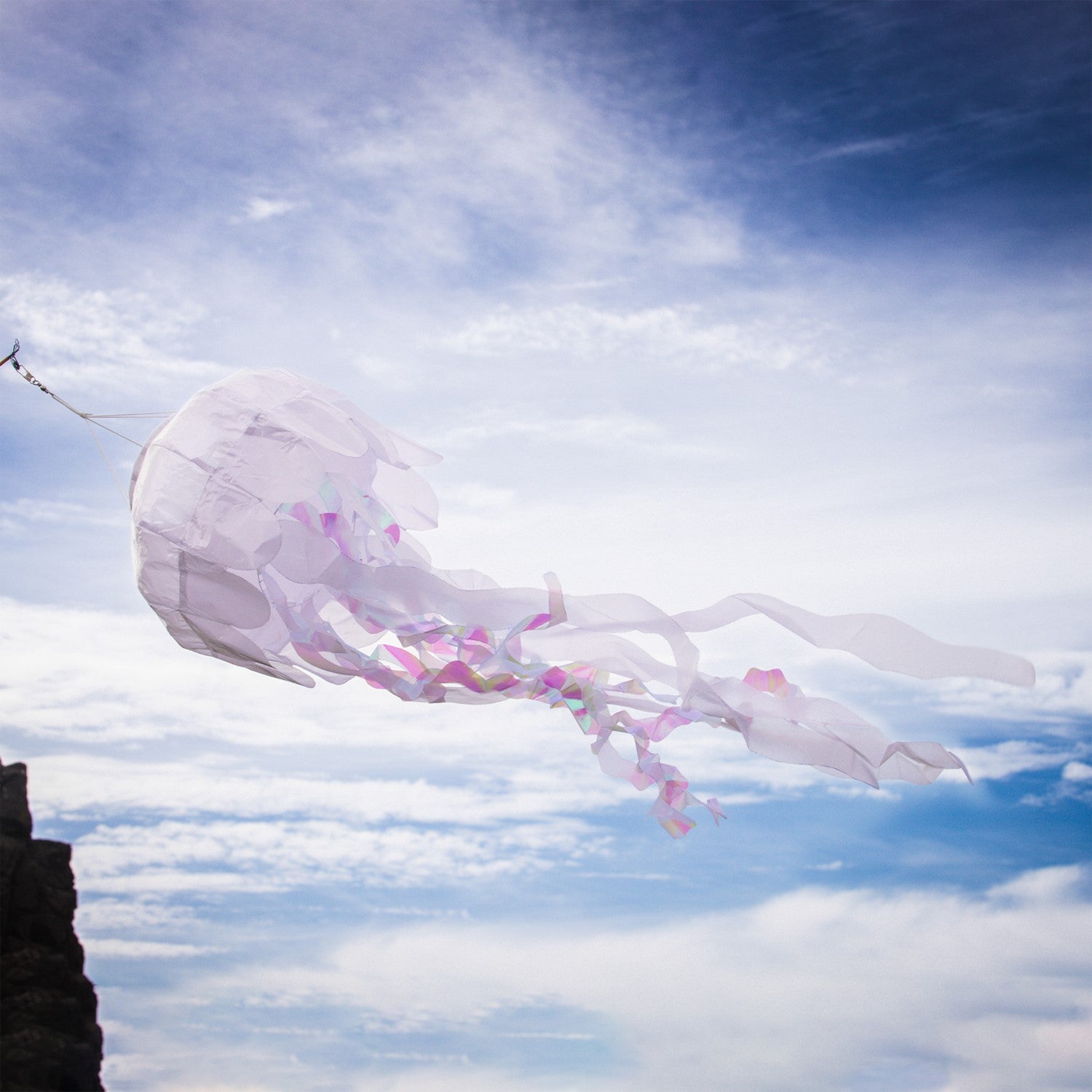 A 40-inch White Iridescent Jellyfish 3D Windsock swaying in the wind, highlighting its shimmering fabric and lifelike tentacles.