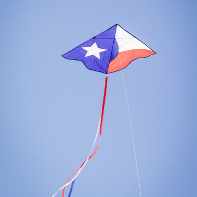 46-inch Texas Delta Kite showcasing a vibrant Lone Star design with colorful 12-foot streamers flying against a clear blue sky.