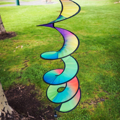 48-inch Jewel Curlie featuring a rainbow design, elegantly swirling and suspended in an outdoor garden setting.