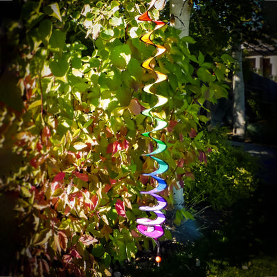 48-inch Rainbow Thin Curlie hanging in a garden, showcasing vibrant colors and a whimsical design that spins in the breeze.