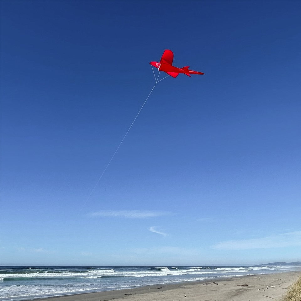 5' 3D Red Shark Kite showcasing its dynamic 3D design, with tooth-lined jaws and tail, flying gracefully against a clear blue sky.