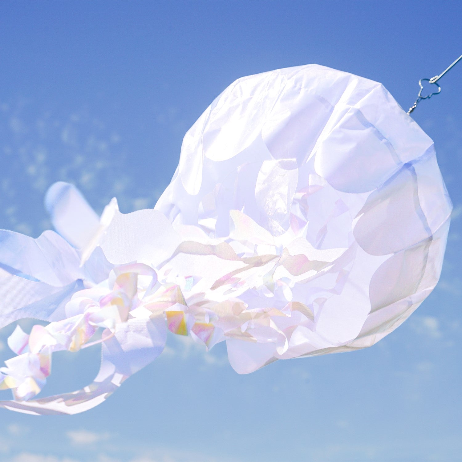 50-inch White Iridescent Jellyfish 3D Windsock with flowing tentacles, displayed outdoors, capturing sunlight with stunning iridescent colors.