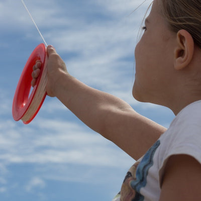 50 LB x 300' kite line on hoop featuring twisted polyester, red plastic hoop, and attached snap swivel for easy connectivity displayed outdoors.