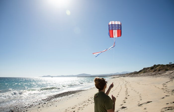The 5.0 Stars and Stripes Air Foil Kite features vibrant red, white, and blue colors in a stars and stripes design, ready to soar high in the sky with ease.