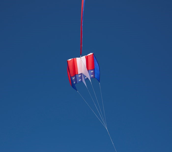 The 5.0 Stars and Stripes Air Foil Kite features vibrant red, white, and blue colors in a stars and stripes design, ready to soar high in the sky with ease.