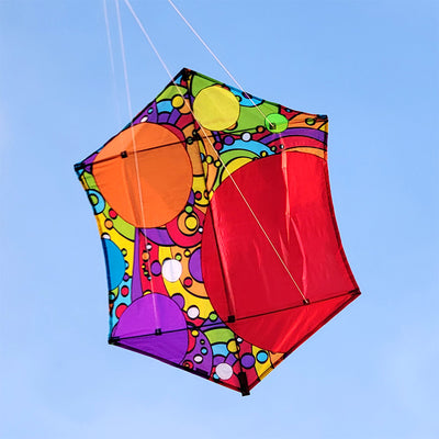 A 56 in. Rokkaku Kite featuring a rainbow bubbles design soaring in the sky against a blue backdrop, displayed with its frame and line.