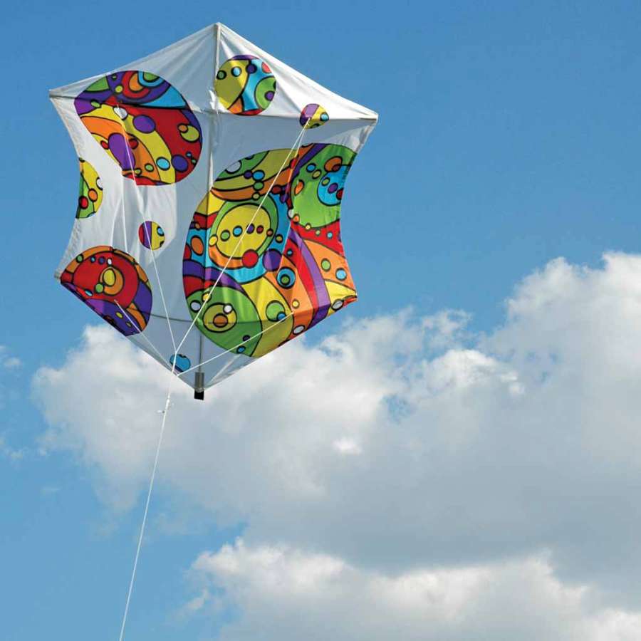 56 in. Rokkaku Kite - Rainbow Orbit in flight, showcasing its colorful rainbow design against a blue sky with clouds.
