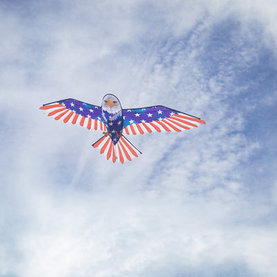 70-inch Patriotic Bald Eagle Kite soaring in the sky, featuring a majestic bald eagle design and American flag patterns against a blue backdrop.